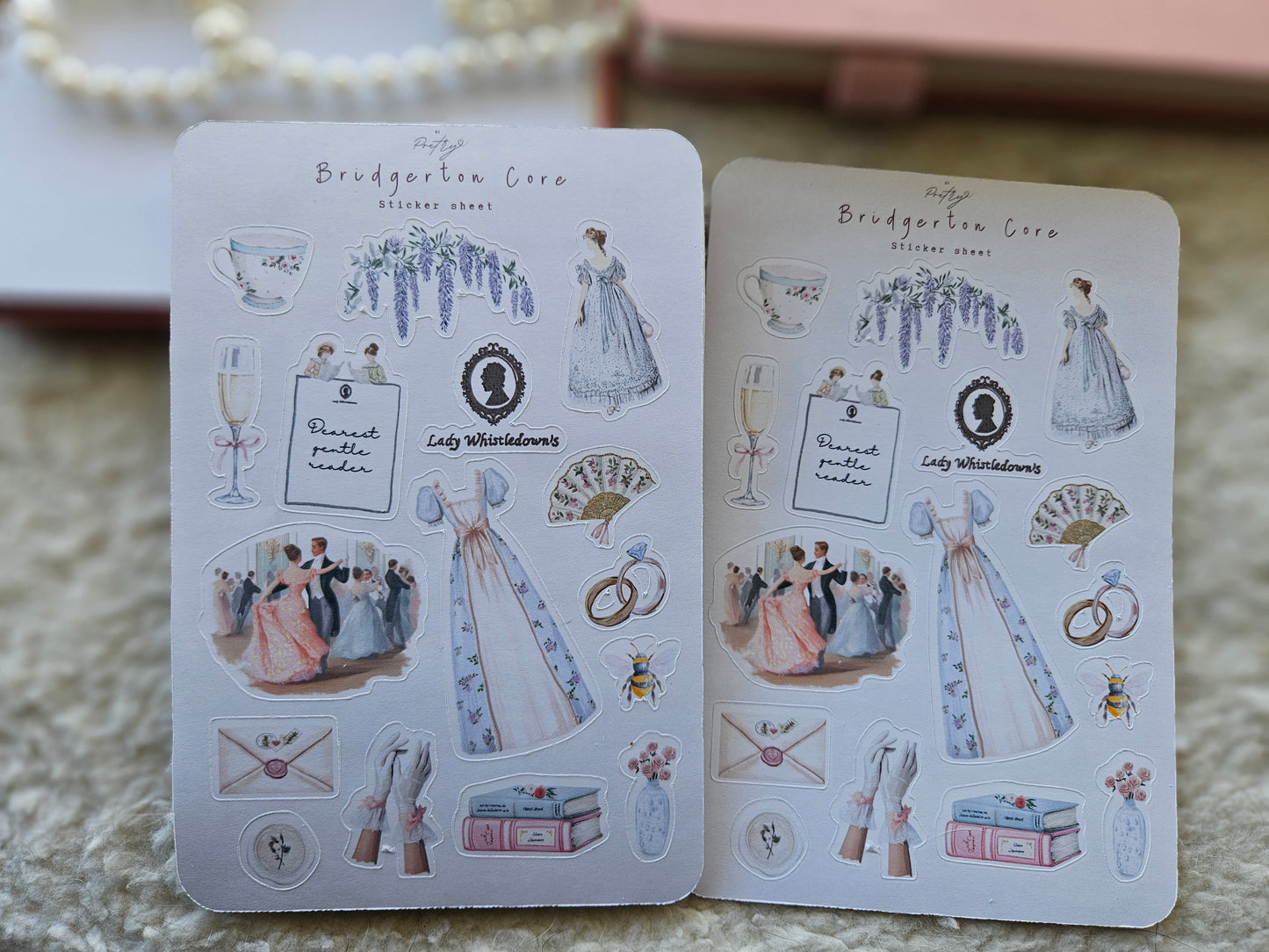 Two open sticker books with illustrated stickers on a textured surface