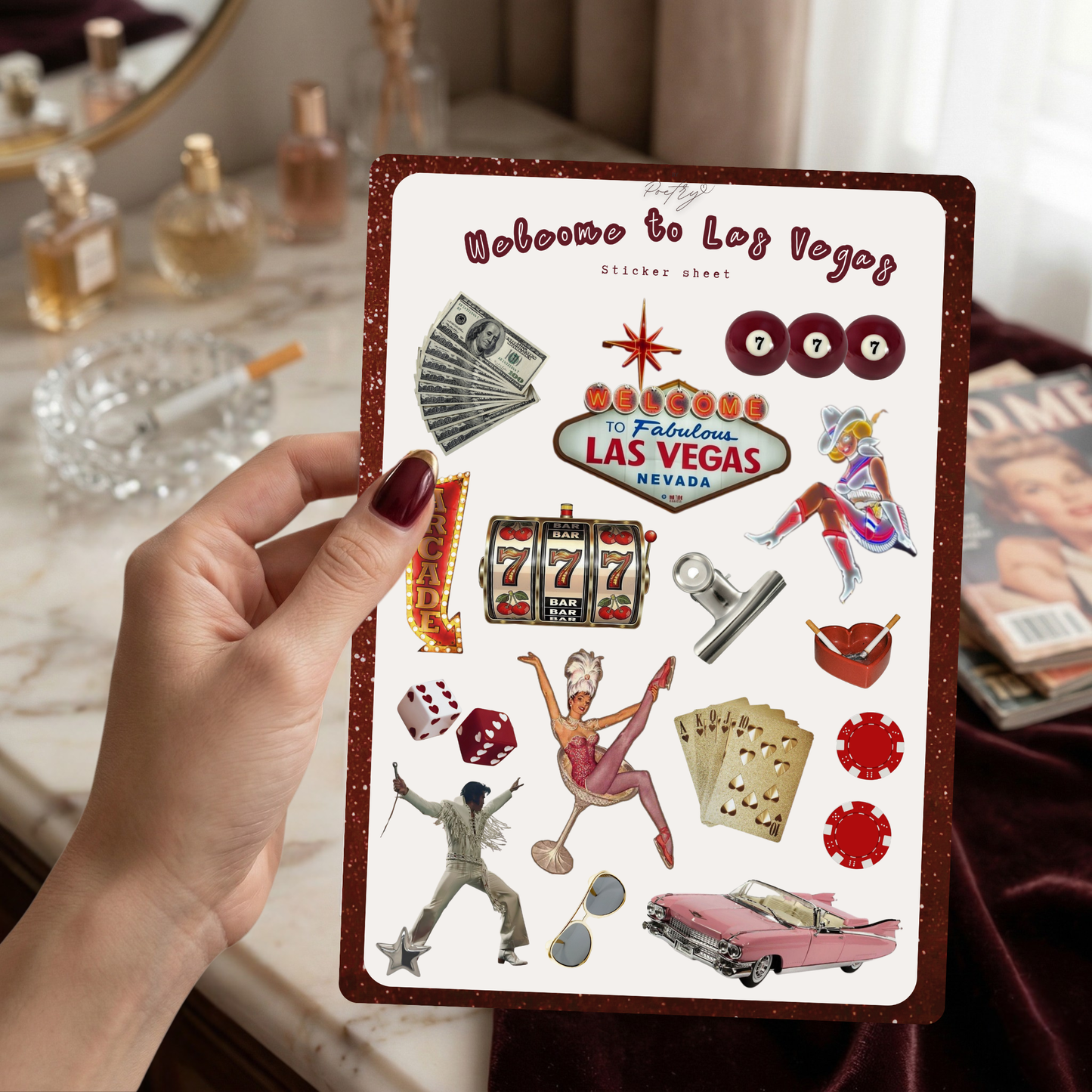 Sticker sheet with Las Vegas-themed designs held by a hand, with a vanity table in the background.