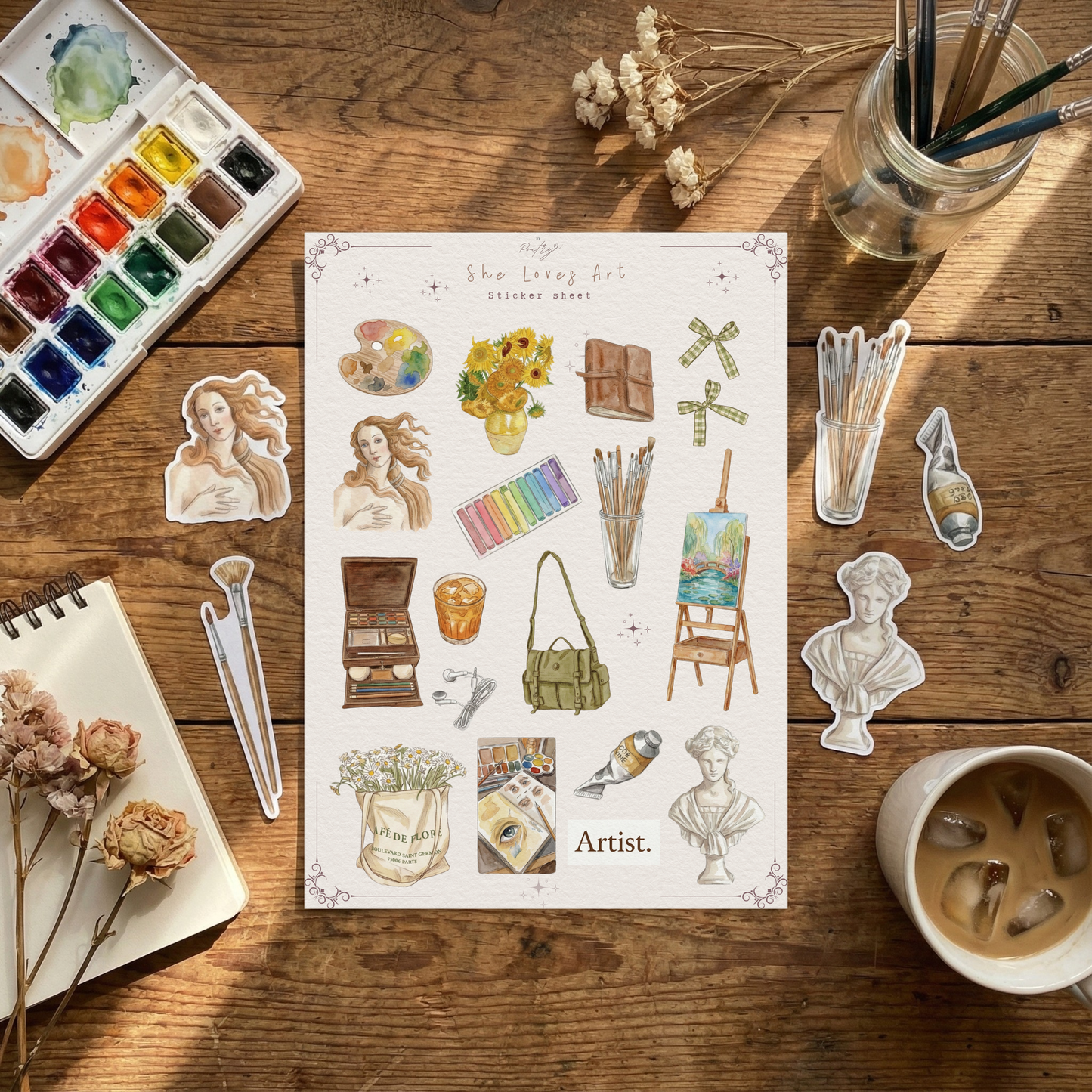 Sheet of stickers with artistic designs on a wooden table with art supplies.